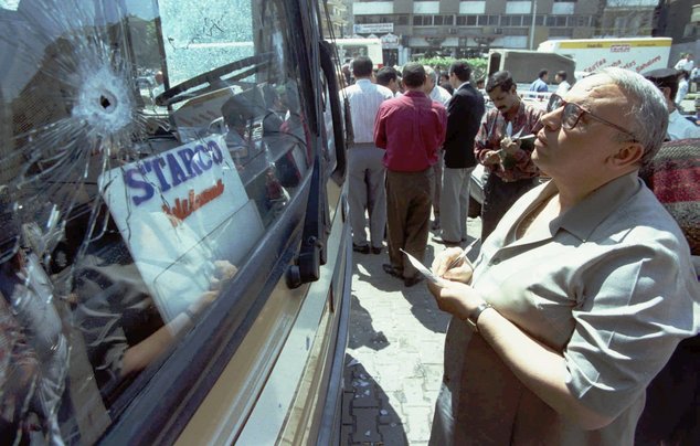 FILE - In this April 18, 1996 file photo, a Egyptian police investigator inspects the bullet-hit windshield of tourist bus at the entrance of hotel Europa in Cairo, Egypt. Four Islamic militants opened fire on Greek tourists in Cairo, killing 18 people outside Hotel. (AP Photo/Enric Marti, File)
