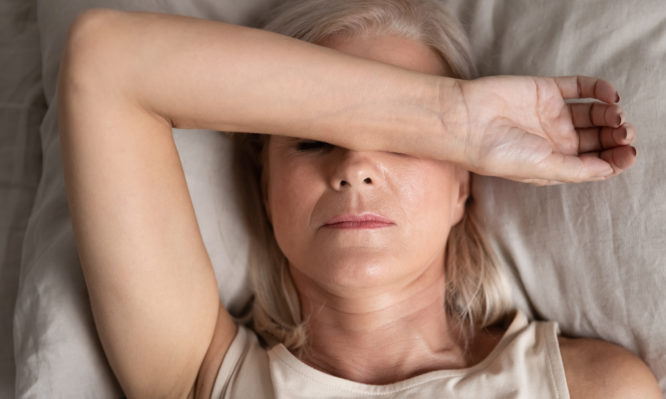 Close up top view middle-aged woman lying down in bed on pillow put hand on face, concept of female having insomnia sleeping disorder or migraine pain, melancholic mood, personal life troubles concept
