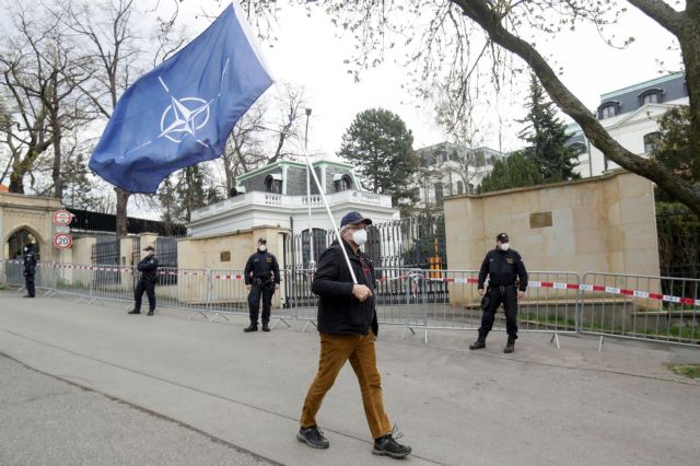 A man carrying a NATO flag, to protest over Russian intelligence services alleged involvement in an ammunition depot explosion in Vrbetice area in 2014, walks past police officers outside the Russian Embassy in Prague, Czech Republic April 18, 2021. REUTERS/David W Cerny