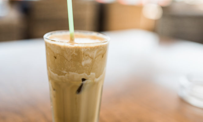 Close up shot of a coffee frappe. Coffee frappe is a cold variation of instant coffee drink with foam being whizzed out of coffee and milk added with lots of ice and water.