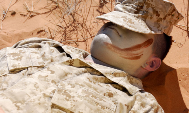 Lone Marine Lying Down In The Desert Sand Resting.  Hat On Shading Eyes.
