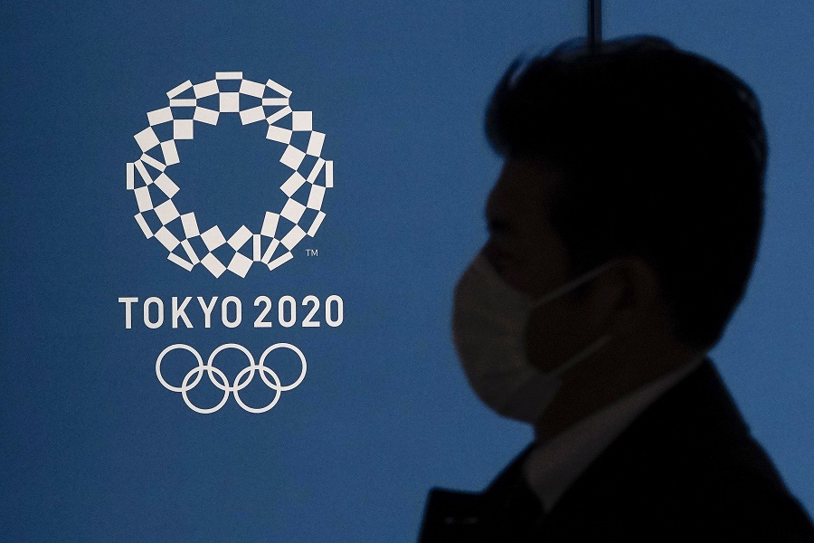 epa08318051 (FILE) - A pedestrian wearing a protective face mask walks past the emblem of the Tokyo Olympic Games in Tokyo, Japan, 23 March 2020 (re-issued on 24 March 2020). The International Olympic Committee (IOC) on 24 March 2020 announced that the Tokyo 2020 Olympic Games will be postponed to 2021 due to the ongoing coronavirus COVID-19 pandemic.  EPA/KIMIMASA MAYAMA
