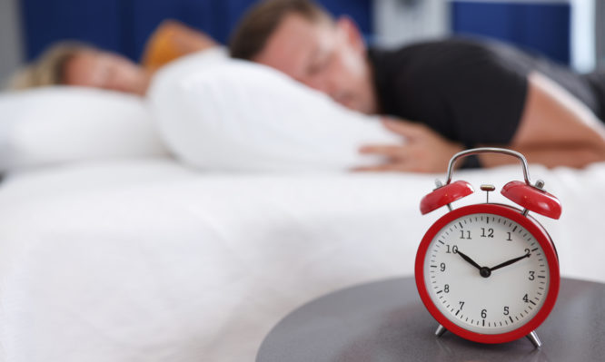 Man and woman sleep in bedroom on alarm clock at ten in morning. Late night sleep weekend concept
