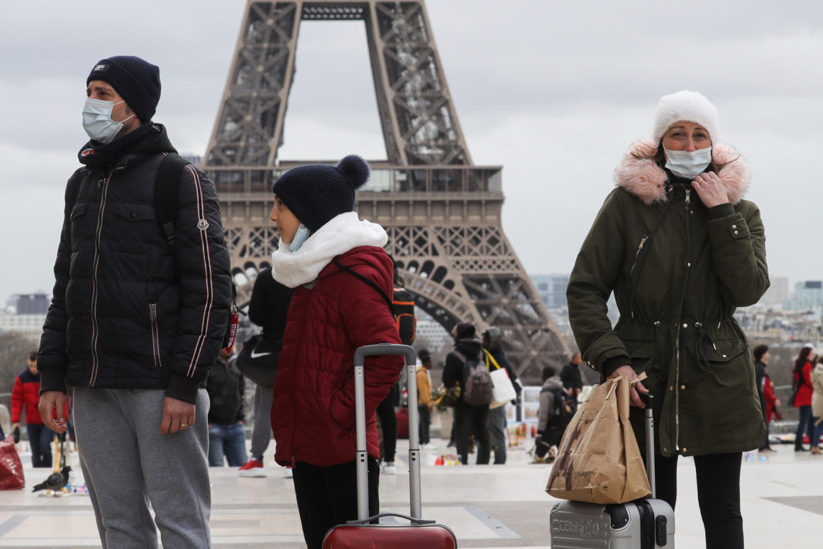 People wear a protective facemask as they walk in front the Eiffel tower, in Paris, on March 12, 2020 during a world COVID-19 outbreak. - The novel coronavirus "is a controllable pandemic" if countries step up measures to tackle it, the head of the World Health Organization (WHO) said March 12, 2020. More than 4,500 people have died, according to an AFP tally, while the WHO said some 125,000 cases had been reported from 118 countries and territories. The pandemic has disrupted cultural and sporting events around the world as authorities try to prevent large gatherings. (Photo by Ludovic Marin / AFP) (Photo by LUDOVIC MARIN/AFP via Getty Images)