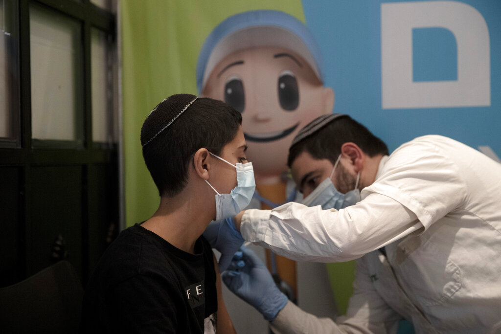 A 14-year-old Israeli receives a booster shot of the coronavirus vaccine at Clalit Health Service's center in the Cinema City complex in Jerusalem, Wednesday, Sept. 22, 2021. Israel is pressing ahead with its aggressive campaign of offering coronavirus boosters to almost anyone over 12 and says its approach was further vindicated by a U.S. decision to give the shots to older patients or those at higher risk. (AP Photo/Maya Alleruzzo)