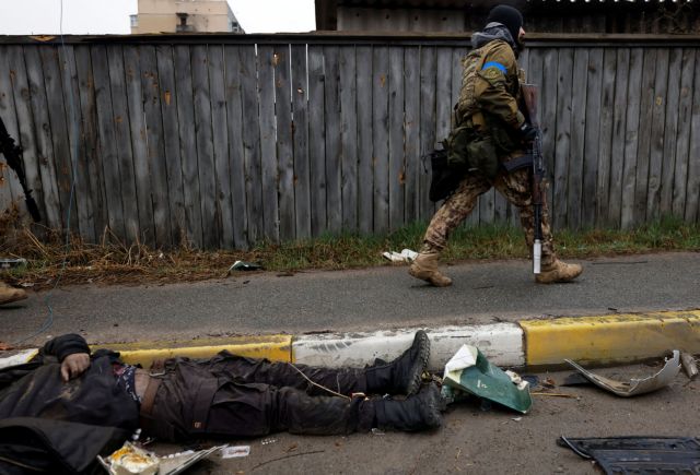 SENSITIVE MATERIAL. THIS IMAGE MAY OFFEND OR DISTURB    A Ukrainian soldier walks past the body of a civilian, who according to residents was killed by Russian army soldiers, as it lies on the street, amid Russia's invasion of Ukraine, in Bucha,  in Kyiv region April 2, 20022. REUTERS/Zohra Bensemra