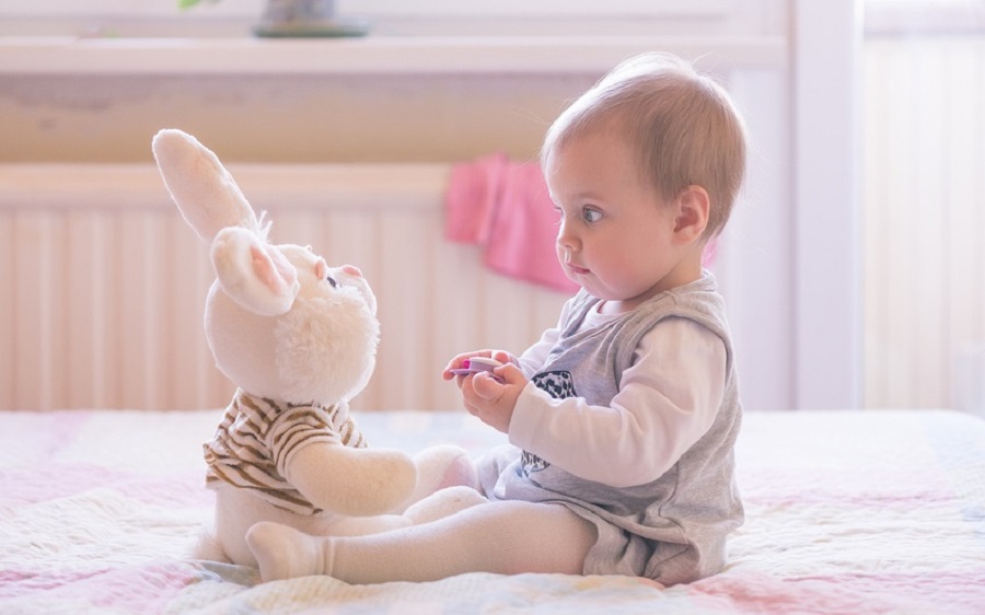 10 months old baby girl playing with plush rabbit