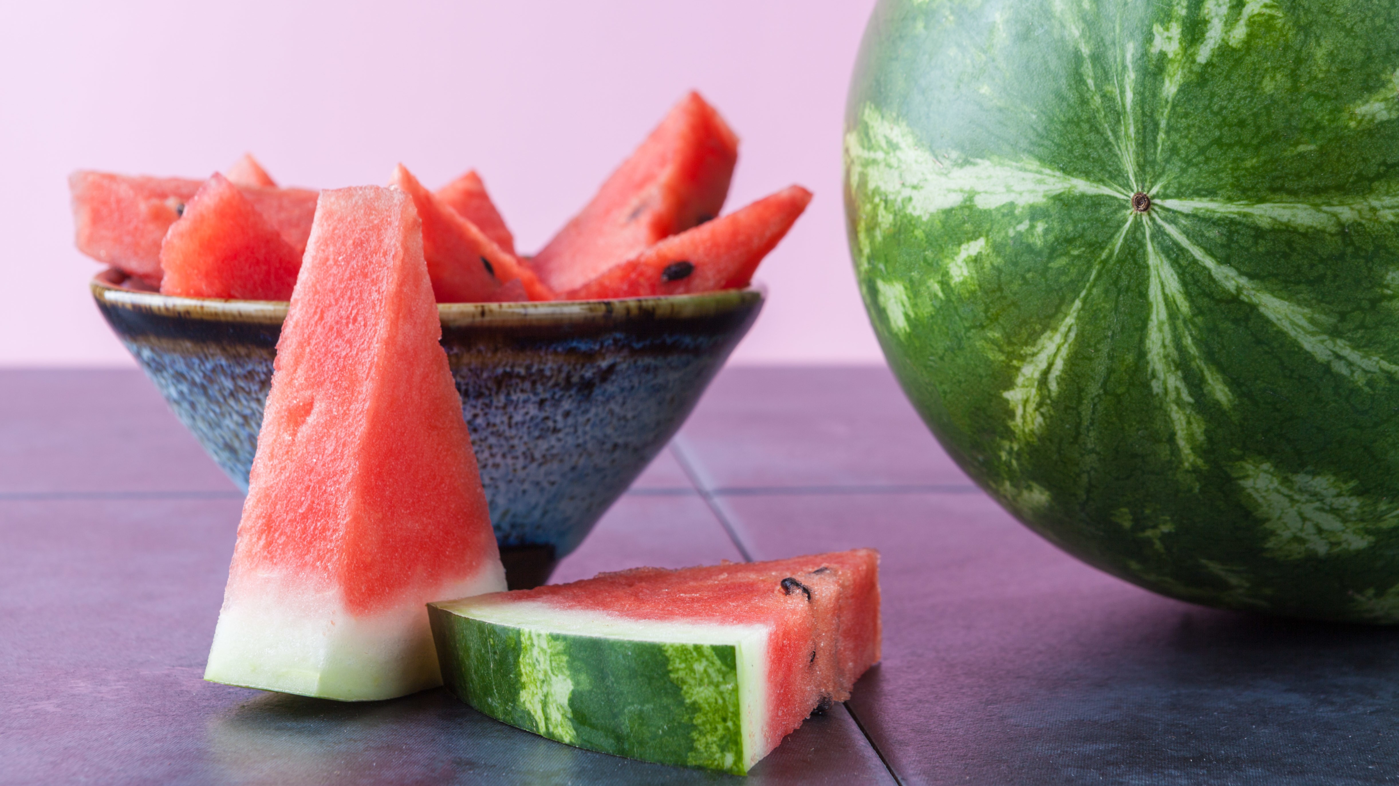 Whole watermelon and slices in ceramic bowl with copy space. Shallow depth of field.