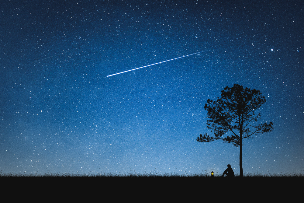 silhouette-man-sitting-mountain-night-sky-with-shooting-star-alone-concept