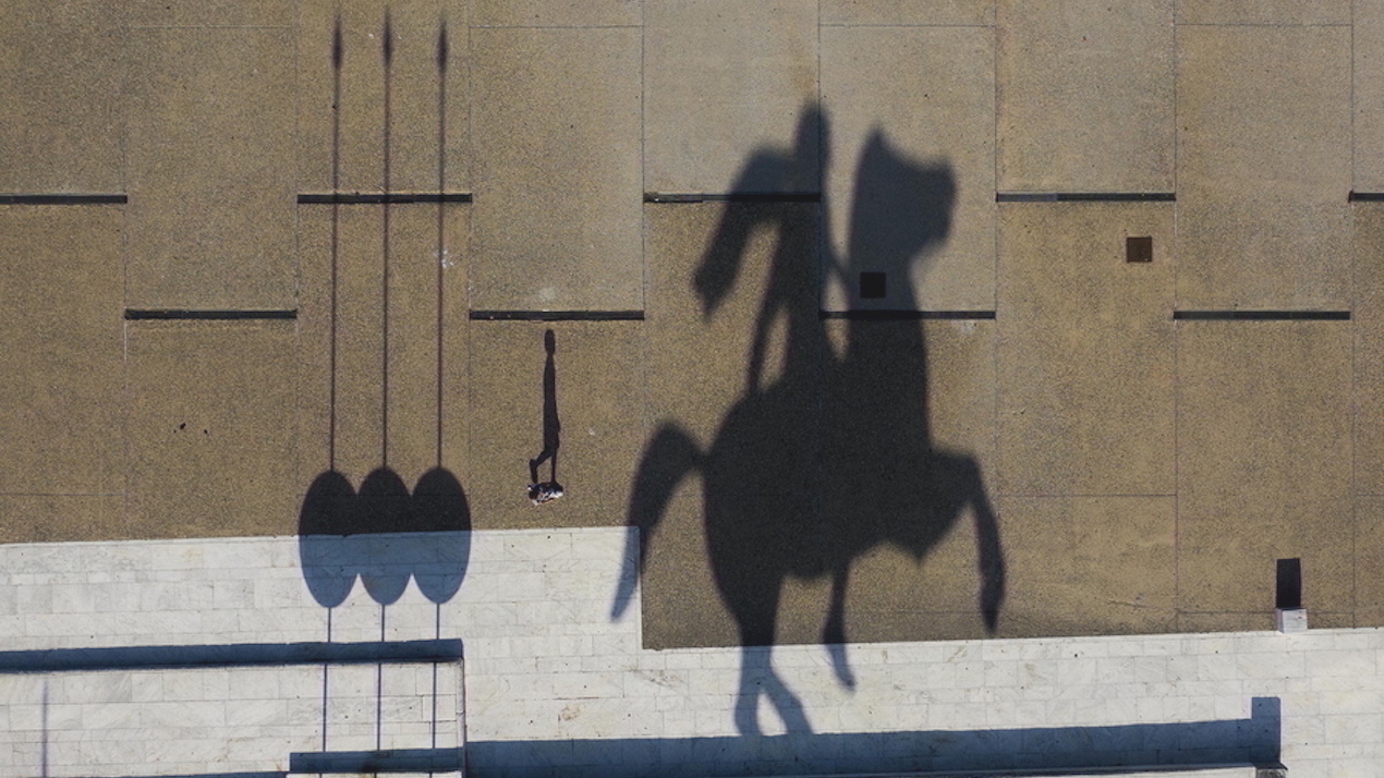 epa08775344 A picture taken with a drone shows a man walking at the waterfront  as the shadow of a staute of Alexander the Great is silhouetted, in Thesssaloniki, Greece, 26 October 2020.  EPA/DIMITRIS TOSIDIS