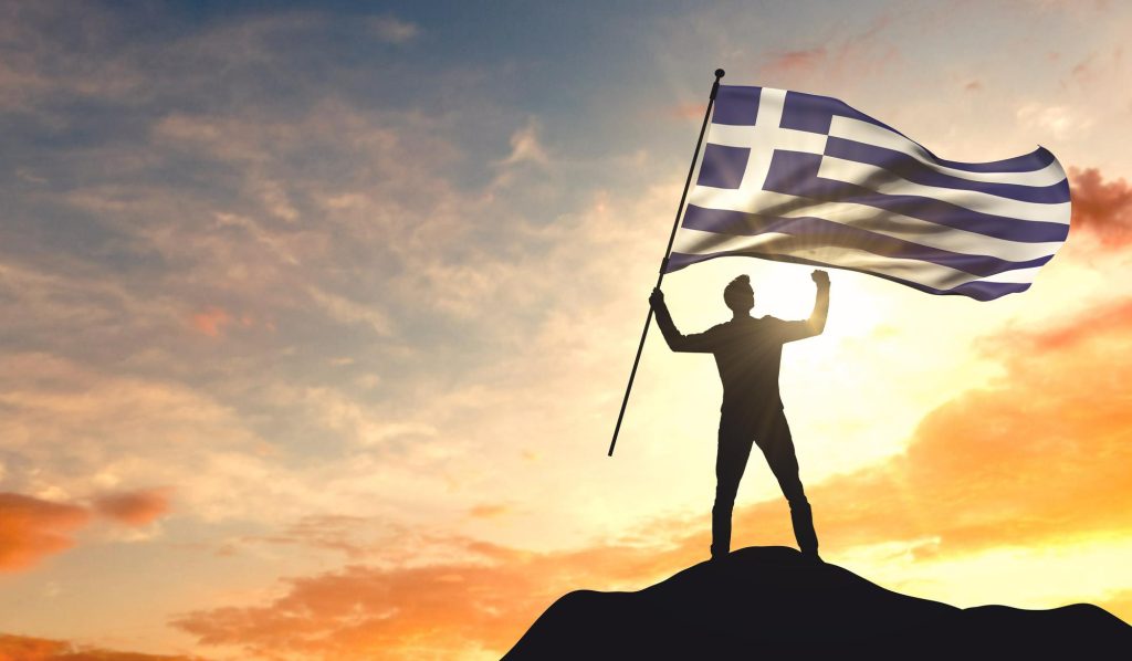 greece-flag-being-waved-by-man-celebrating-success-top-mountain-3d-rendering-1024x598