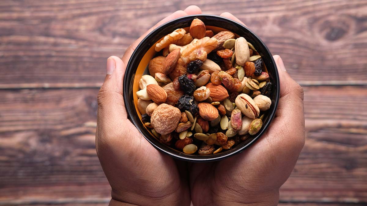 Hand holding a bowl of mixed nut top down.