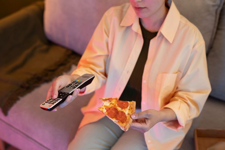 young-woman-eating-pizza-watching-tv